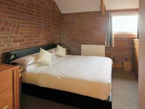 1 dormitorio con cama blanca y pared de ladrillo en Yarlington Mill, en Ledbury