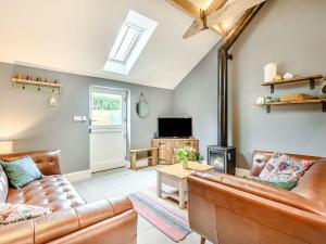 a living room with two leather couches and a tv at The Cow Shed - Uk38575 in Aston Cantlow