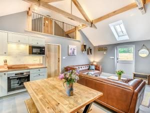 cocina y sala de estar con mesa de madera en The Cow Shed - Uk38575, en Aston Cantlow
