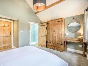 1 dormitorio con 1 cama grande y espejo en The Cow Shed - Uk38575, en Aston Cantlow