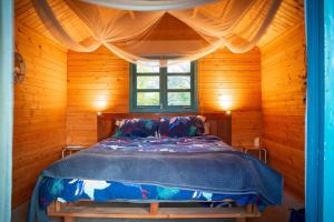 a bed in a wooden room with a window at Tui Ridge Eco Cabins in Aongatete
