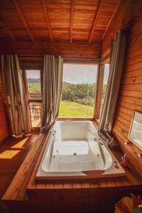 a bath tub in a room with a large window at Refúgio do Sol Campestre in Urubici