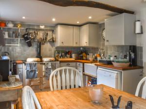 a kitchen with white cabinets and a wooden table at Chapel Cottage, in Holmbury Saint Mary