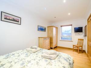 a bedroom with a bed and a desk and a tv at Riof Ocean Cottage - Uk7125 in Valtos