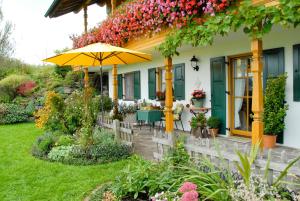 Cette maison dispose d'une terrasse avec un parasol et des fleurs. dans l'établissement Ferienwohnung Freißl, à Rottenbuch