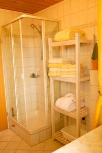 ein Badezimmer mit Dusche und einige Handtücher auf Regalen in der Unterkunft Ferienwohnung Freißl in Rottenbuch