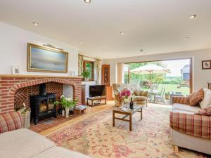a living room with a fireplace and a couch and chairs at Riversdale Cottage in Neatishead