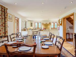 a long wooden table with chairs and a kitchen at Riversdale Cottage in Neatishead