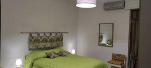 a bedroom with a green bed and a mirror at Il Quadrifoglio di Triveri in Bovalino Marina