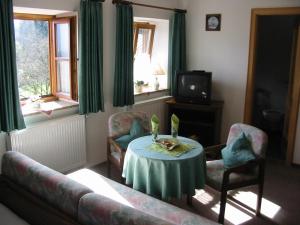ein Wohnzimmer mit einem Tisch, 2 Stühlen und einem TV in der Unterkunft Berggasthof Oberkälberstein in Berchtesgaden