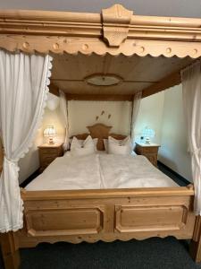Un dormitorio con una gran cama de madera con sábanas blancas. en Hotel Almenrausch en Neukirchen