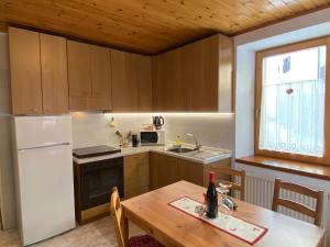 eine Küche mit einem Holztisch und einem weißen Kühlschrank in der Unterkunft Appartamenti Benvenuti in Padola