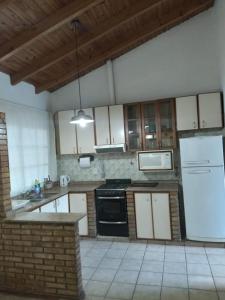 cocina con armarios blancos y nevera blanca en Casa en Mendoza en Godoy Cruz