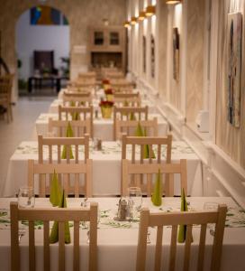 une rangée de tables et de chaises avec des fleurs vertes sur elles dans l'établissement EPRESPARK Panzió, à Vecsés