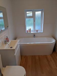 a white bathroom with a tub and a sink at Romsey Brewery House - circa 1893 in Romsey