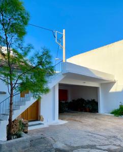 een wit gebouw met een trap en een boom bij Casa Azul in Spáta
