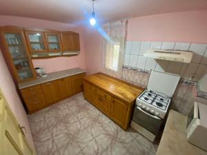 a kitchen with wooden cabinets and a stove at Cabana Corina in Vartop