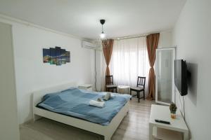 - une chambre avec un lit bleu et une télévision dans l'établissement Garsoniera 2 Mega Mall, à Bucarest