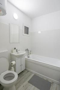La salle de bains blanche est pourvue de toilettes et d'un lavabo. dans l'établissement Garsoniera 2 Mega Mall, à Bucarest