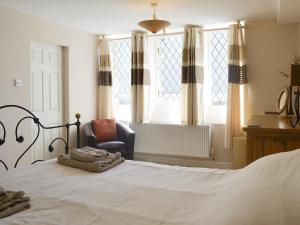 a bedroom with a bed and a chair and windows at Old Church School in Plympton