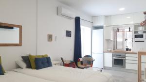 a white bedroom with a bed and a kitchen at HD Mogán Coral Apartments in Puerto de Mogán