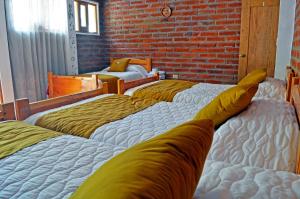 four beds in a room with a brick wall at Lagoon Hotel Chugchilan in Chugchilán