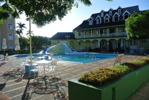 ein großes Gebäude mit einem Pool mit Tischen und Stühlen in der Unterkunft Beach Studio 9 in Ocho Rios