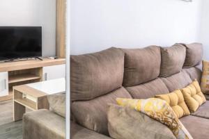 ein Wohnzimmer mit einem braunen Sofa und einem Tisch in der Unterkunft Brisa Marinera Grupo AC Gestion in Cádiz