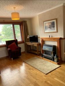 a living room with a fireplace and a chair and a desk at Stornoway Holiday Let in Stornoway