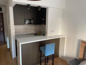 a small kitchen with a counter and a blue stool at Apartment Maximus II lux in Novi Beograd