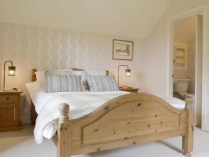 a bedroom with a wooden bed with white sheets and blue pillows at Green Lane Cottage in Newtown