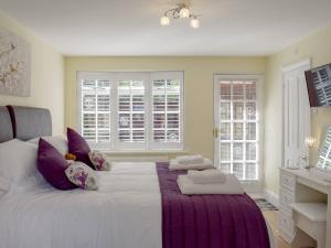 a bedroom with a large white bed with purple pillows at The Coach House in Wootton Bridge