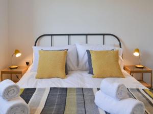 a bedroom with a white bed with two chairs at Avocet Cottage in Sheringham