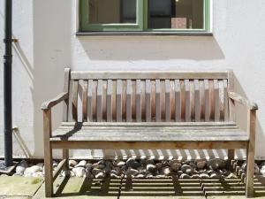 a wooden bench sitting in front of a window at Avocet Cottage in Sheringham