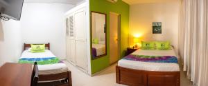 1 dormitorio con 2 camas, paredes verdes y mesa en Hotel Country Boutique, en Piura