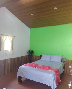 1 dormitorio con 1 cama con pared verde en Pochote Lodge, en Guayabos