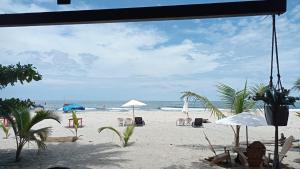 a beach with chairs and umbrellas and the ocean at Cabaña The Sunset in Santa Marta