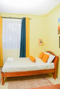 a bed with orange pillows in a room with a window at Naivasha Southlake apartments in Naivasha