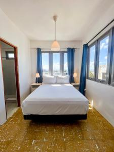 a bedroom with a large white bed with blue curtains at Urbana Hotel in San Juan