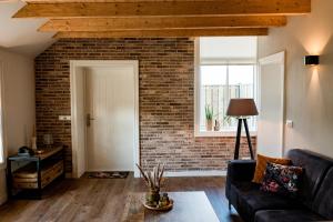 a living room with a brick wall and a couch at Landelijk gelegen vakantiewoning in Oldebroek