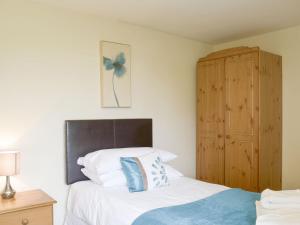 Schlafzimmer mit einem Bett und einem Holzschrank in der Unterkunft Rose Farm Cottage in Frostenden