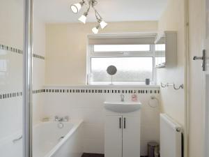 ein weißes Bad mit einem Waschbecken und einer Dusche in der Unterkunft Rose Farm Cottage in Frostenden