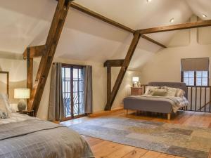 a bedroom with two beds and wooden beams at The Barn in Chipperfield