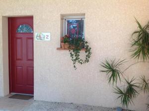 a red door and a window with plants on a building at Meublés de Margastau in Dieupentale