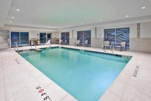 a large swimming pool with blue water in a building at Holiday Inn Express & Suites Okemos - University Area, an IHG Hotel in Okemos