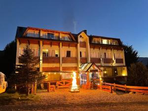 un gran edificio con un fuego delante de él en Hosteria de la Villa y Club Mountain en San Carlos de Bariloche
