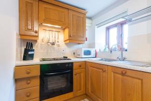 uma cozinha com armários de madeira e um forno com placa de fogão em The Chaff House - farm stay apartment set within 135 acres em Bromyard