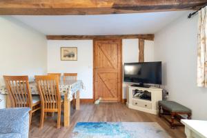 a living room with a dining room table and a tv at The Chaff House - farm stay apartment set within 135 acres in Bromyard