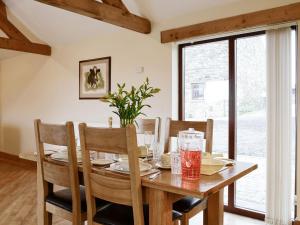 a dining room with a wooden table and chairs at The Old Byre in Dearham