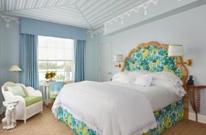 ein Schlafzimmer mit einem großen weißen Bett und einem Stuhl in der Unterkunft The Colony Hotel in Palm Beach